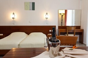 A hotel room with a bed, a desk, and a table with a bottle of champagne. - Villas Duc - Rhodes Island (Rhodes)
