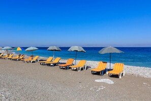 Una playa cerca, sillas reclinables de playa, sombrillas