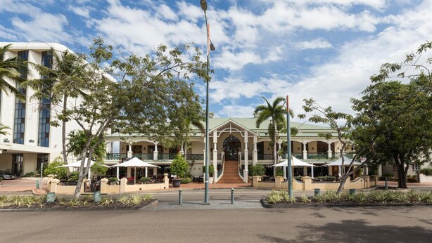 A hotel with a central entrance, outdoor seating, and a clear sky. - Townsville Southbank Apartments (South Townsville)
