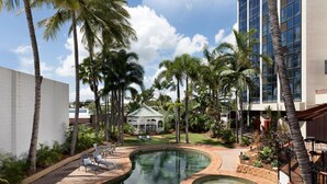 A swimming pool with a circular hot tub, surrounded by palm trees and lounge chairs. - Townsville Southbank Apartments (South Townsville)
