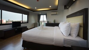 Quarto de hotel moderno com uma cama grande, televisão de tela plana, escrivaninha e vista da cidade através de amplas janelas.