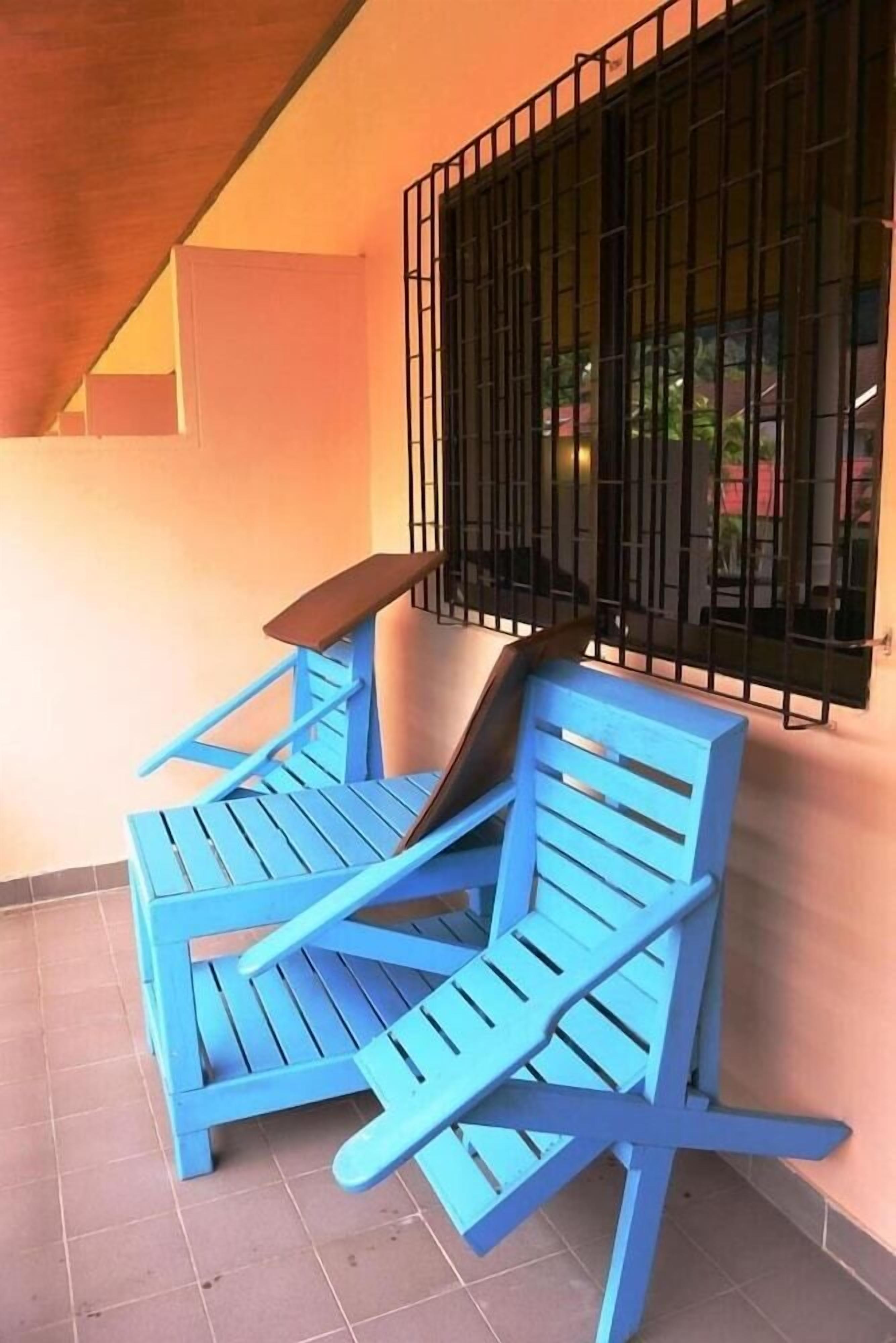 A blue outdoor seating area with a metal railing and a tiled floor.