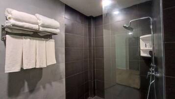 A modern bathroom with dark tiled walls, a glass-enclosed shower, and a towel rack with neatly folded towels.