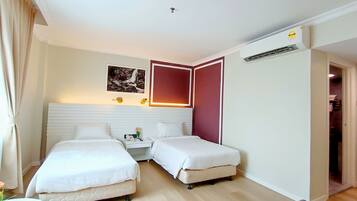 Habitación de hotel con dos camas, una mesita de noche con lámpara, un cuadro en la pared y un equipo de aire acondicionado.