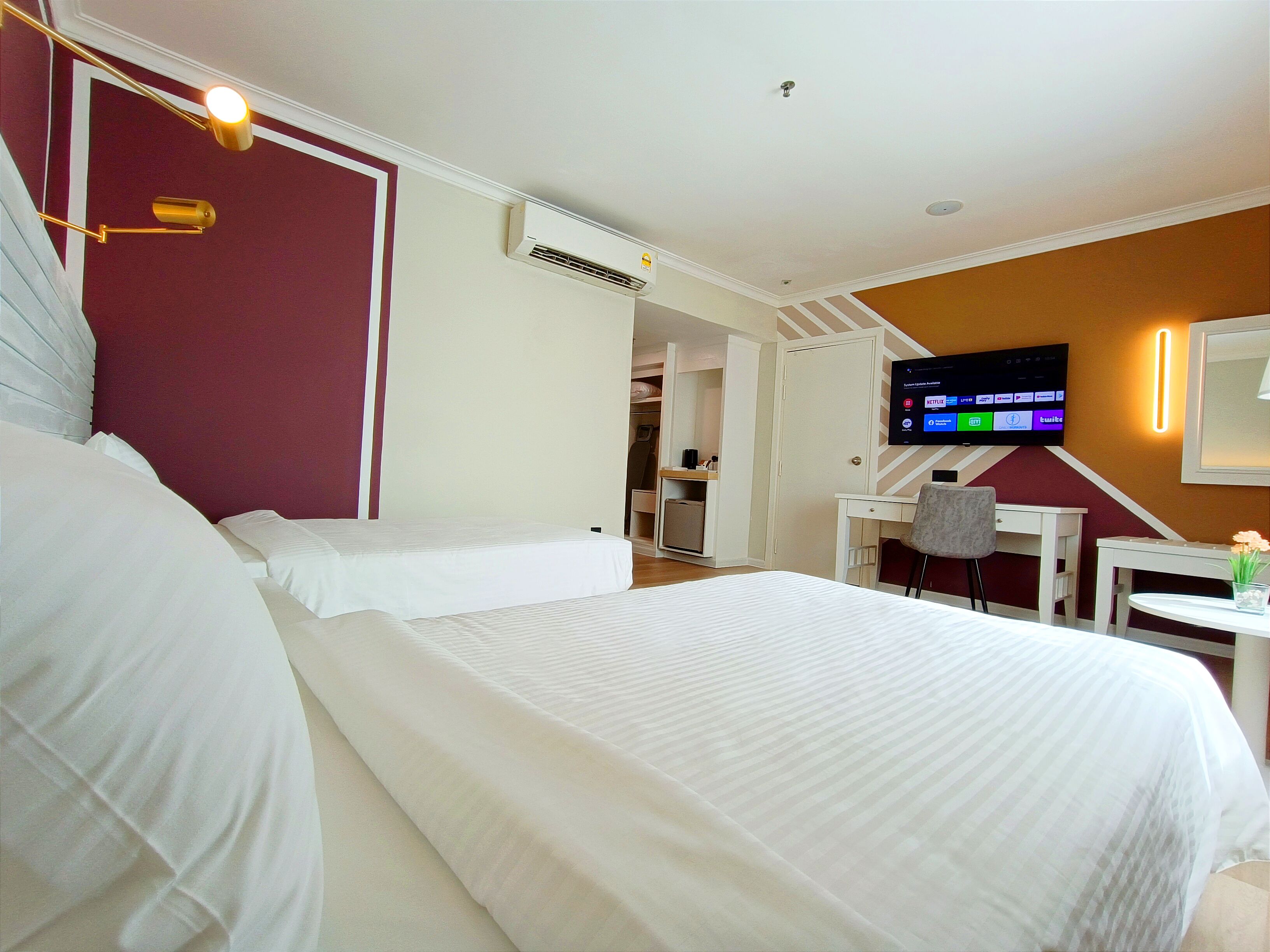 Habitación de hotel con dos camas, televisión, escritorio y una silla.