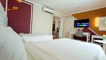 Habitación de hotel con dos camas, televisión, escritorio y una silla.