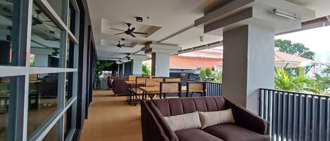 Un espace intérieur moderne comprenant un canapé, des tables et des ventilateurs de plafond.