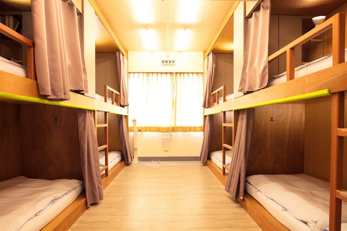 A train compartment with wooden bunk beds, curtains, and a central aisle.