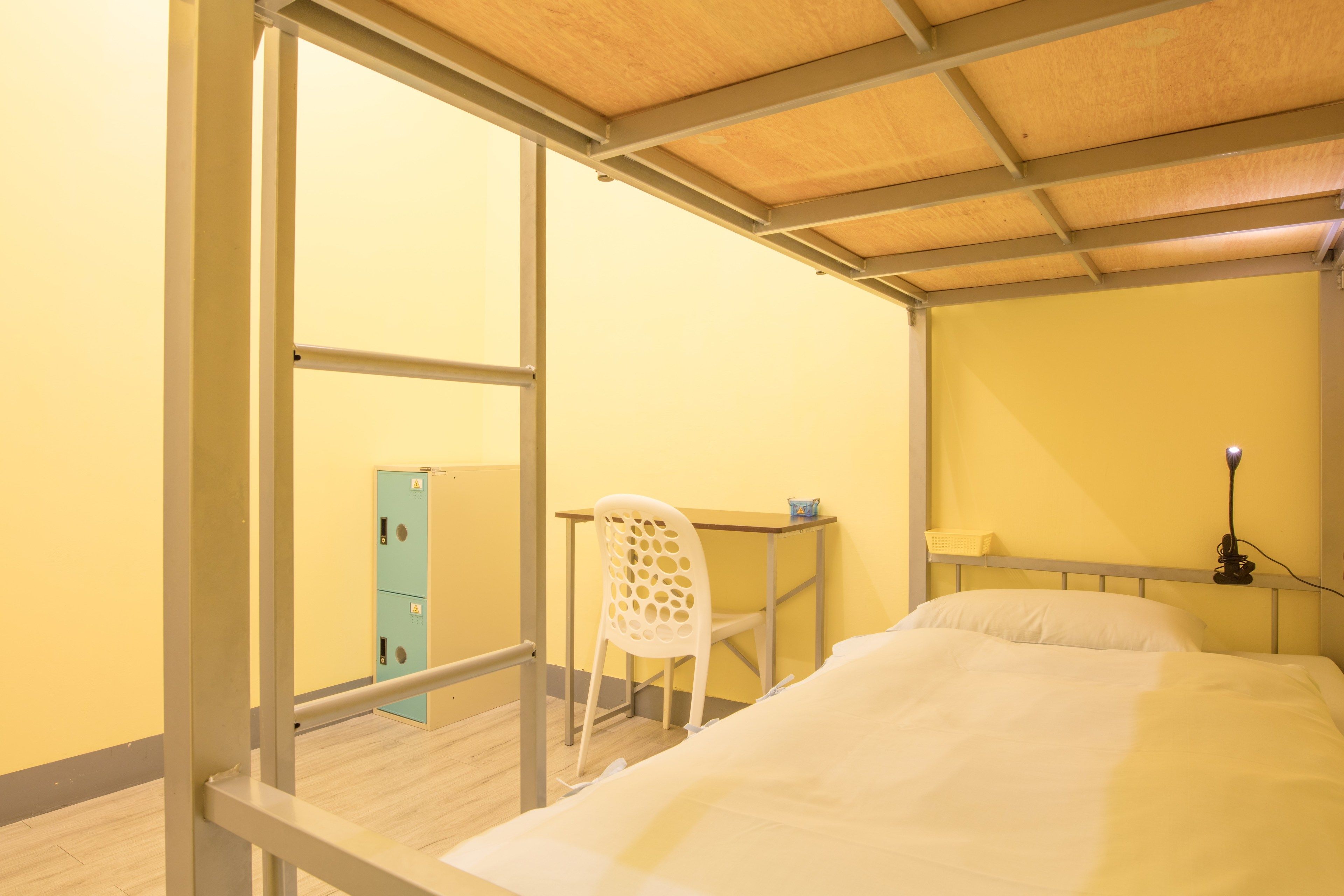 A room with a bed, a desk, a chair, a lamp, and a wardrobe.