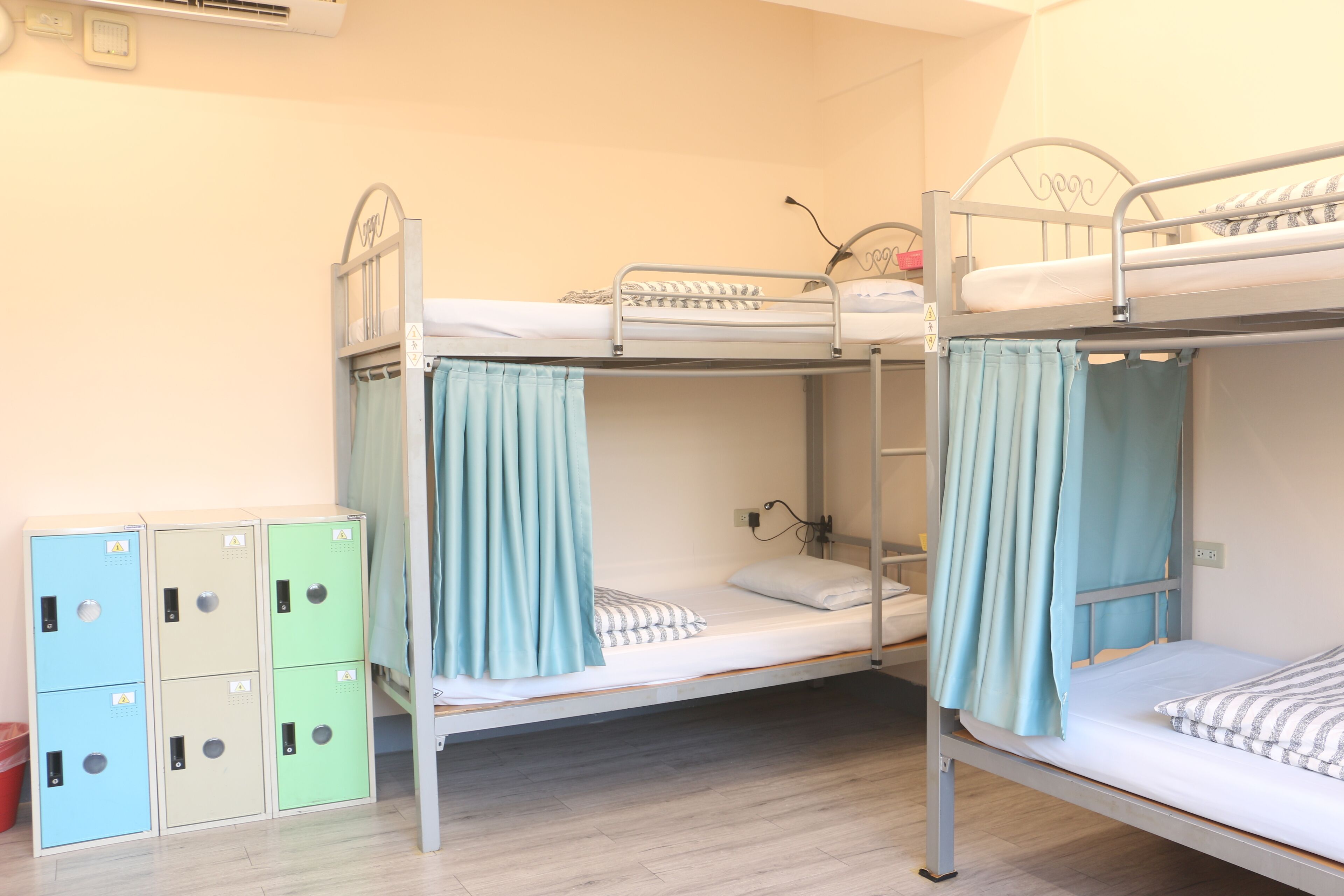 A bunk bed room with a wooden floor, a small desk, and a wardrobe with multiple compartments.