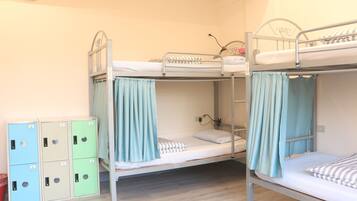 A bunk bed room with a wooden floor, a small desk, and a wardrobe with multiple compartments.