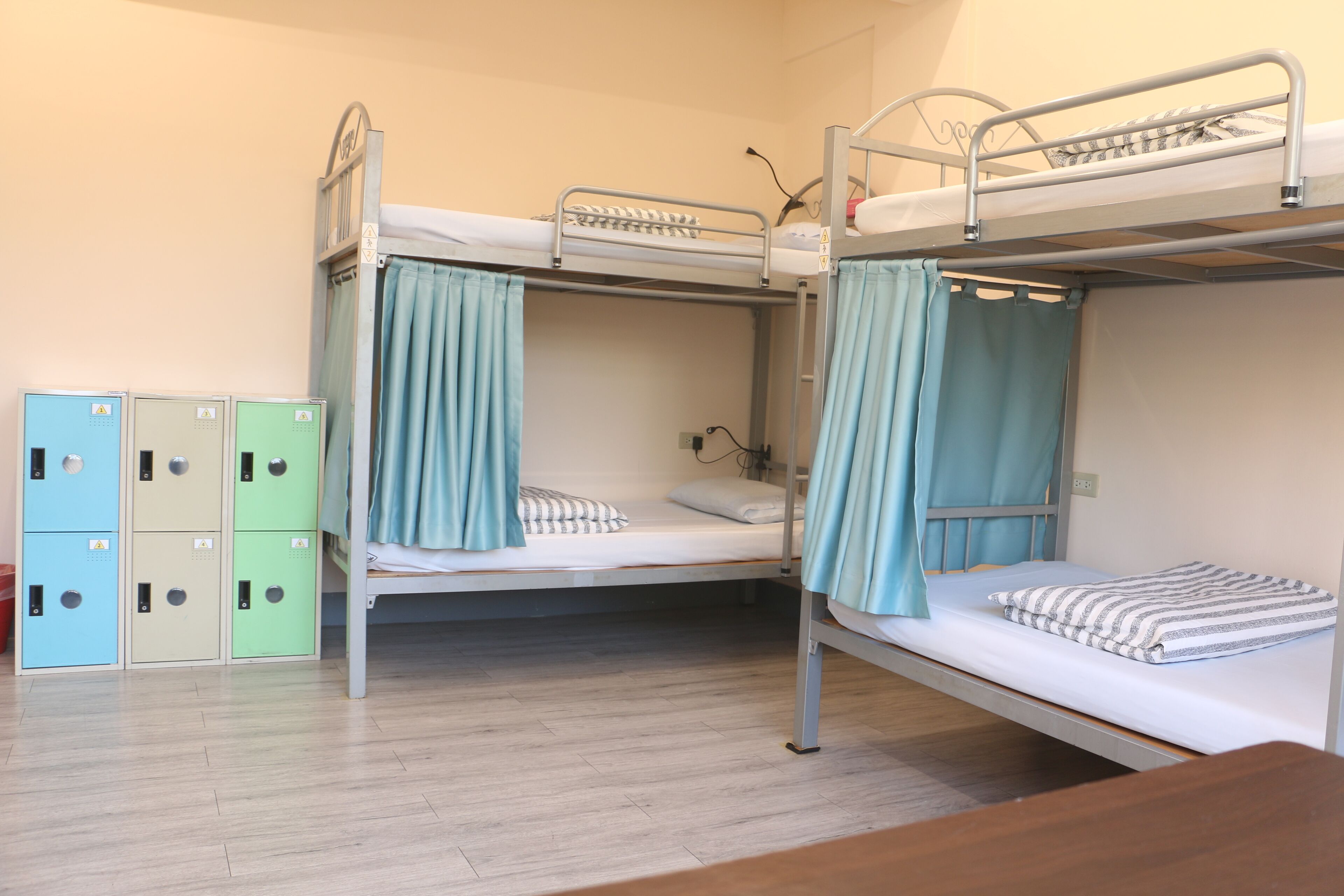 A bunk bed room with a wooden floor, a desk, and storage cabinets.