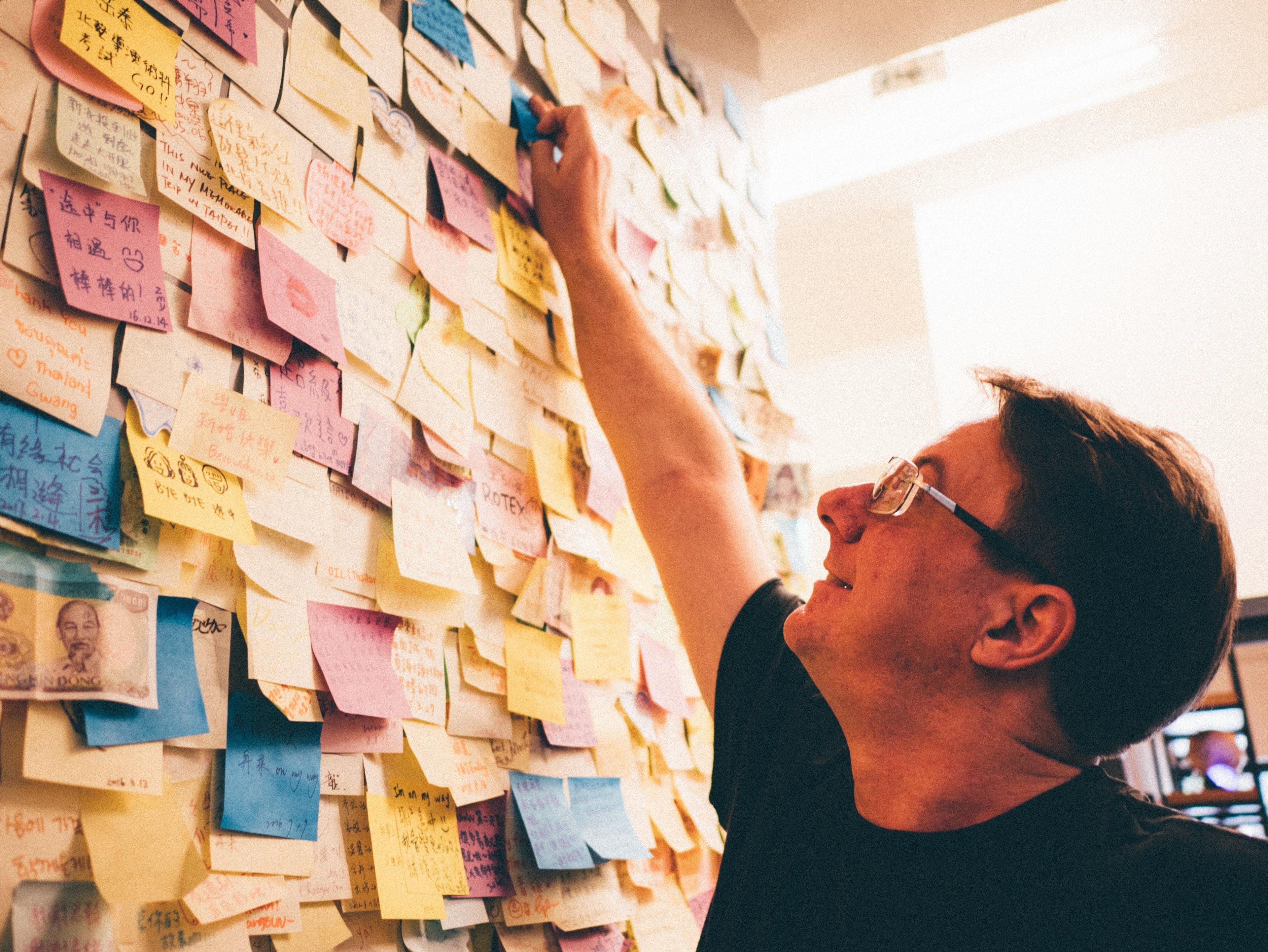 Una persona interactuando con una pared llena de notas y documentos.