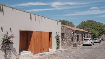Een modern gebouw met een grote houten deur, stenen muren en een straat met kinderkopjes.