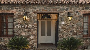 A stone building with a sign reading "CHARCO" and two potted plants in front. - Charco Hotel (Colonia del Sacramento)