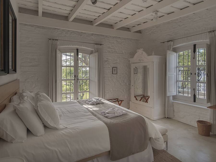 Un dormitorio con una cama grande, dos ventanas, un armario y un televisor.