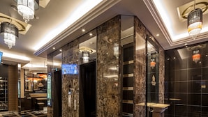 A modern lobby with marble flooring, a digital display, and a reception area. - APA Hotel Higashi Nihombashi Ekimae (Tokyo)