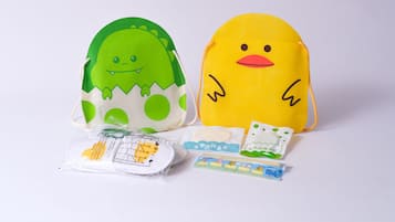 Two plush toys, one green and one yellow, with a small package and a toy train set in front.