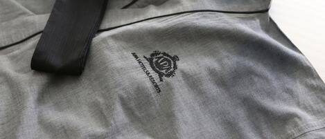 Una bata de hotel gris con una cinta negra y un logotipo que dice 'HOTELRESORTS'.