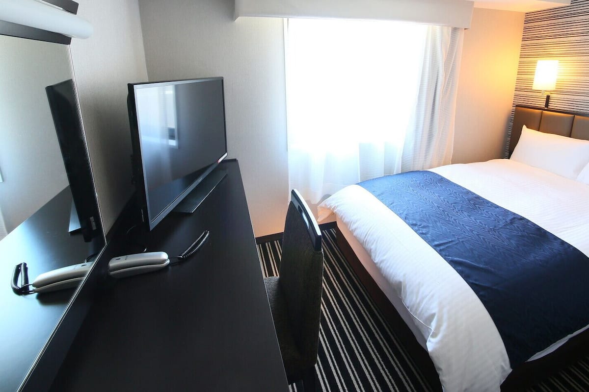 Une chambre d’hôtel avec un lit, une télévision, un bureau et une lampe.