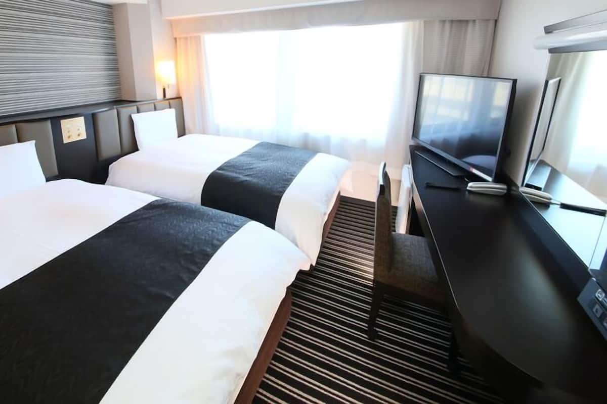 Une chambre d’hôtel avec deux lits, une télévision et un bureau.