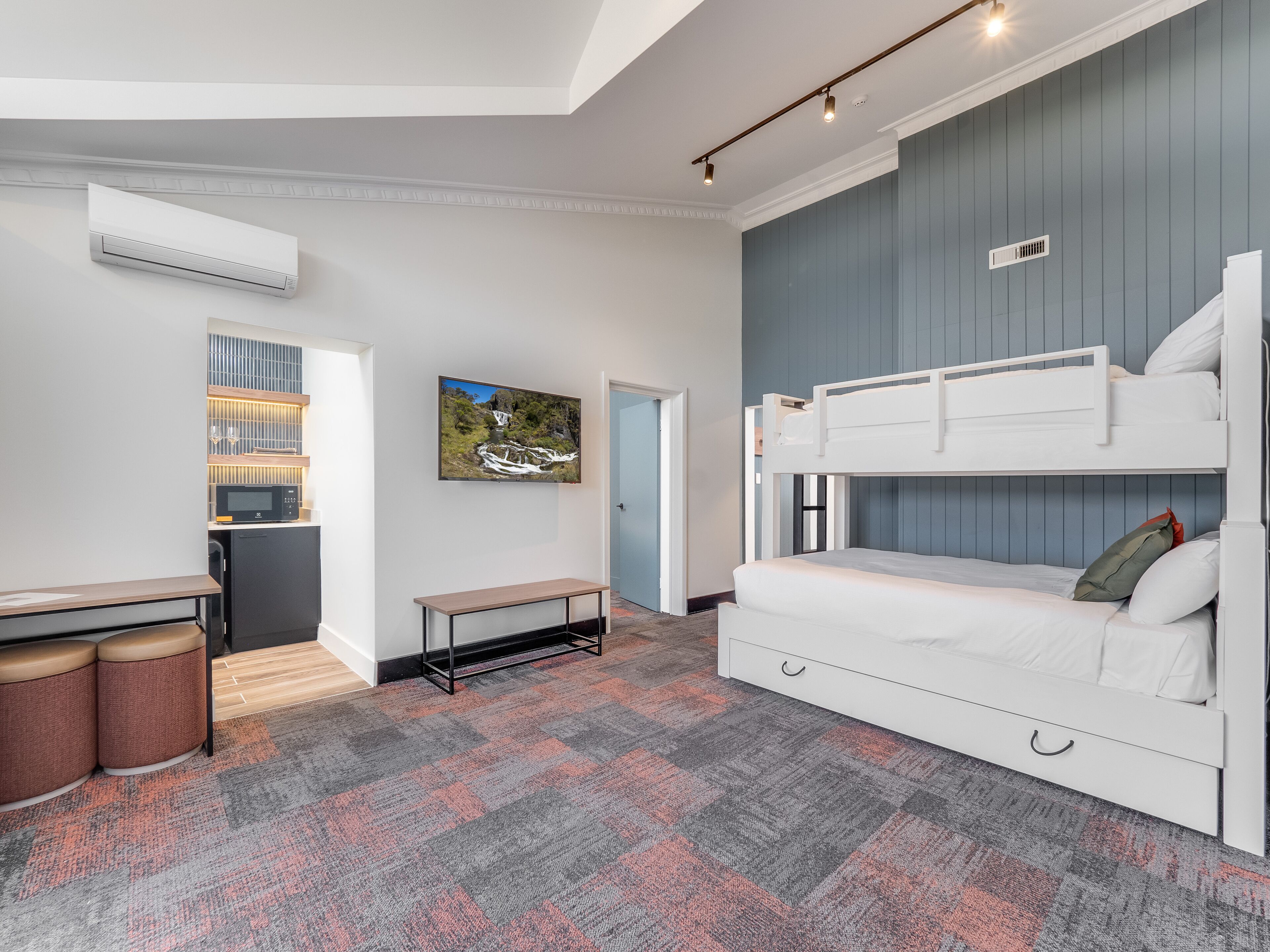 A compact room with bunk beds, a small kitchenette, and a seating area.