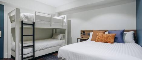 Una habitación de hotel con literas, una cama individual y una mesita de noche.