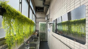 A narrow, tiled corridor with a stainless steel sink and a mirror on the right. - Easymind Guesthouse, Hostel in Taipei Main Station (Taipei)