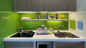 A modern kitchen with green walls, a stainless steel sink, a microwave, and a stove. - Easymind Guesthouse, Hostel in Taipei Main Station (Taipei)