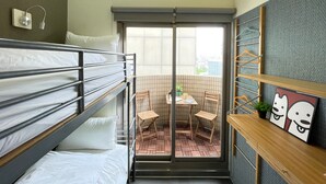 A compact room with bunk beds, a small table with chairs, a potted plant, and a shelf with a picture frame. - Easymind Guesthouse, Hostel in Taipei Main Station (Taipei)