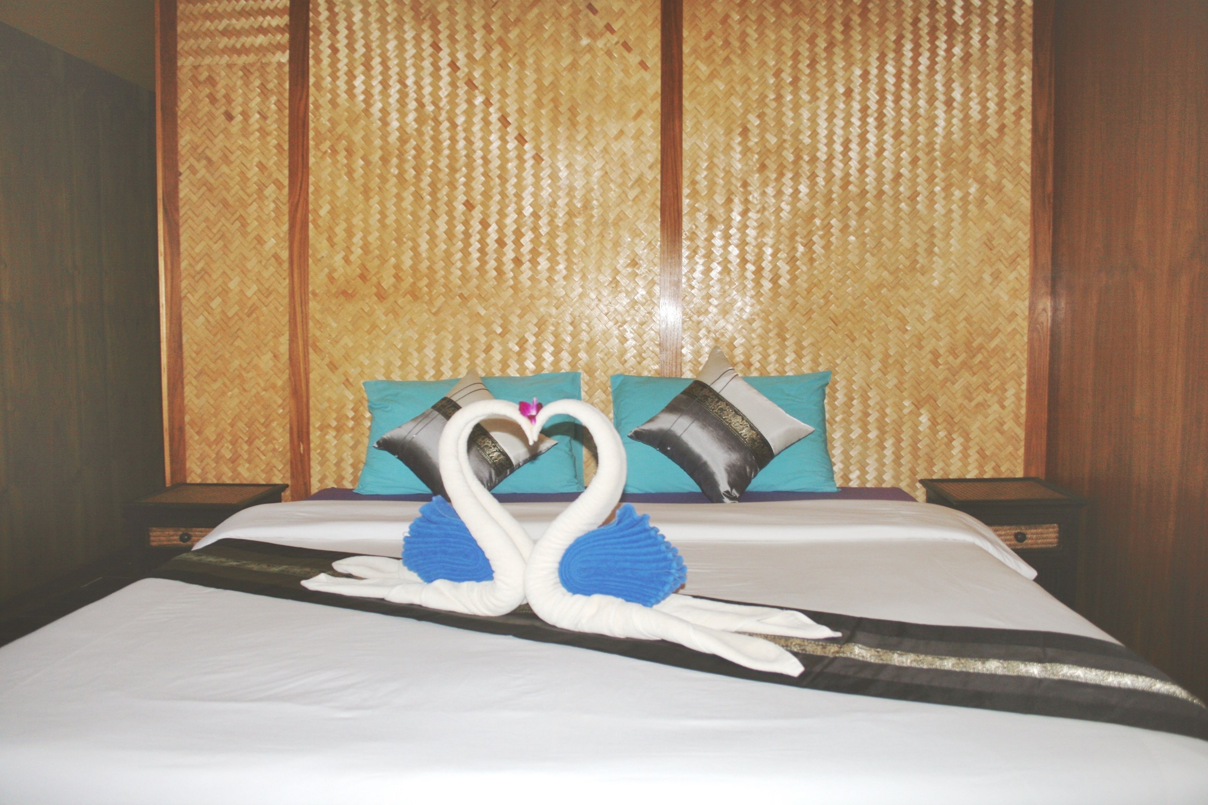 A bed with a decorative swan centerpiece, a woven headboard, and two pillows.