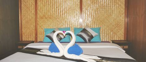 A bed with a decorative swan centerpiece, a woven headboard, and two pillows.