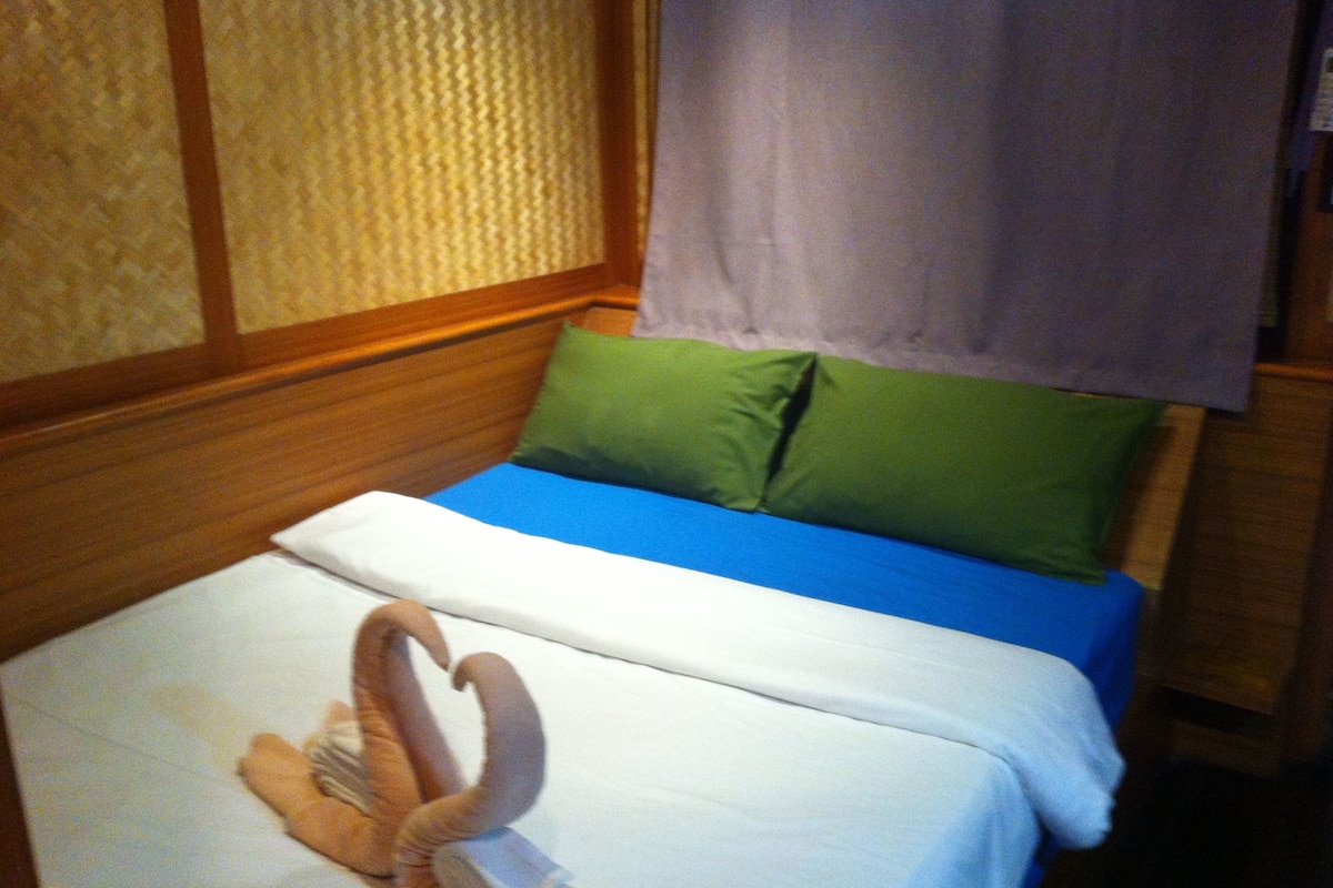 A bed with a blue and green mattress, a white blanket, and a green pillow.