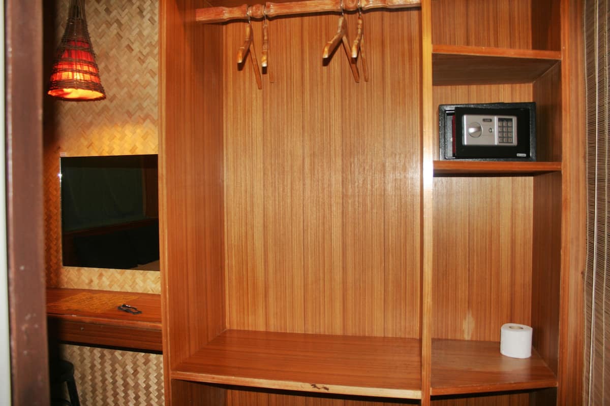 A wooden cabinet with a television, a microwave, and a roll of toilet paper.