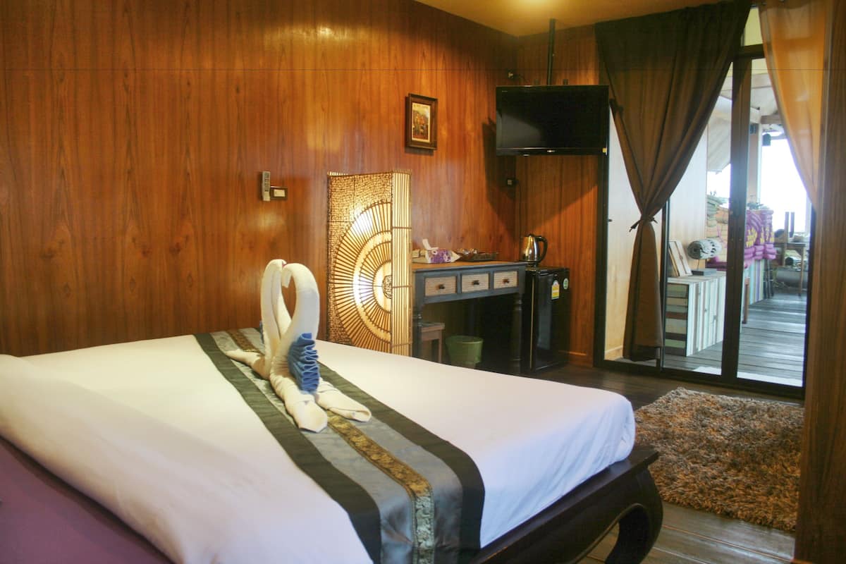 A hotel room with a bed, a desk, a television, and a view of the outside.