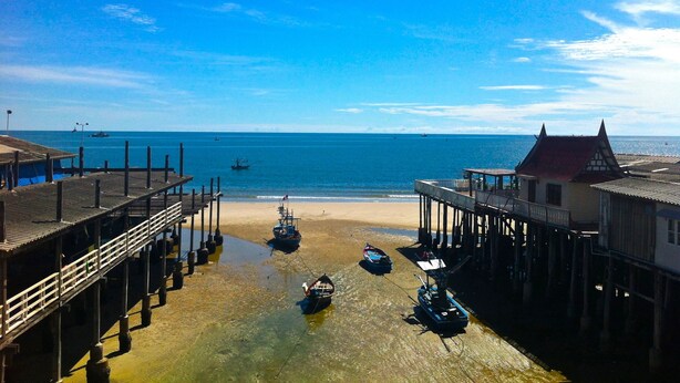 A pier with boats docked, a beach, and the sea in the background. - Sukkasem Homestay (Hua Hin)