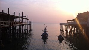 A pier extending into calm water with a boat moored in the center. - Sukkasem Homestay (Hua Hin)