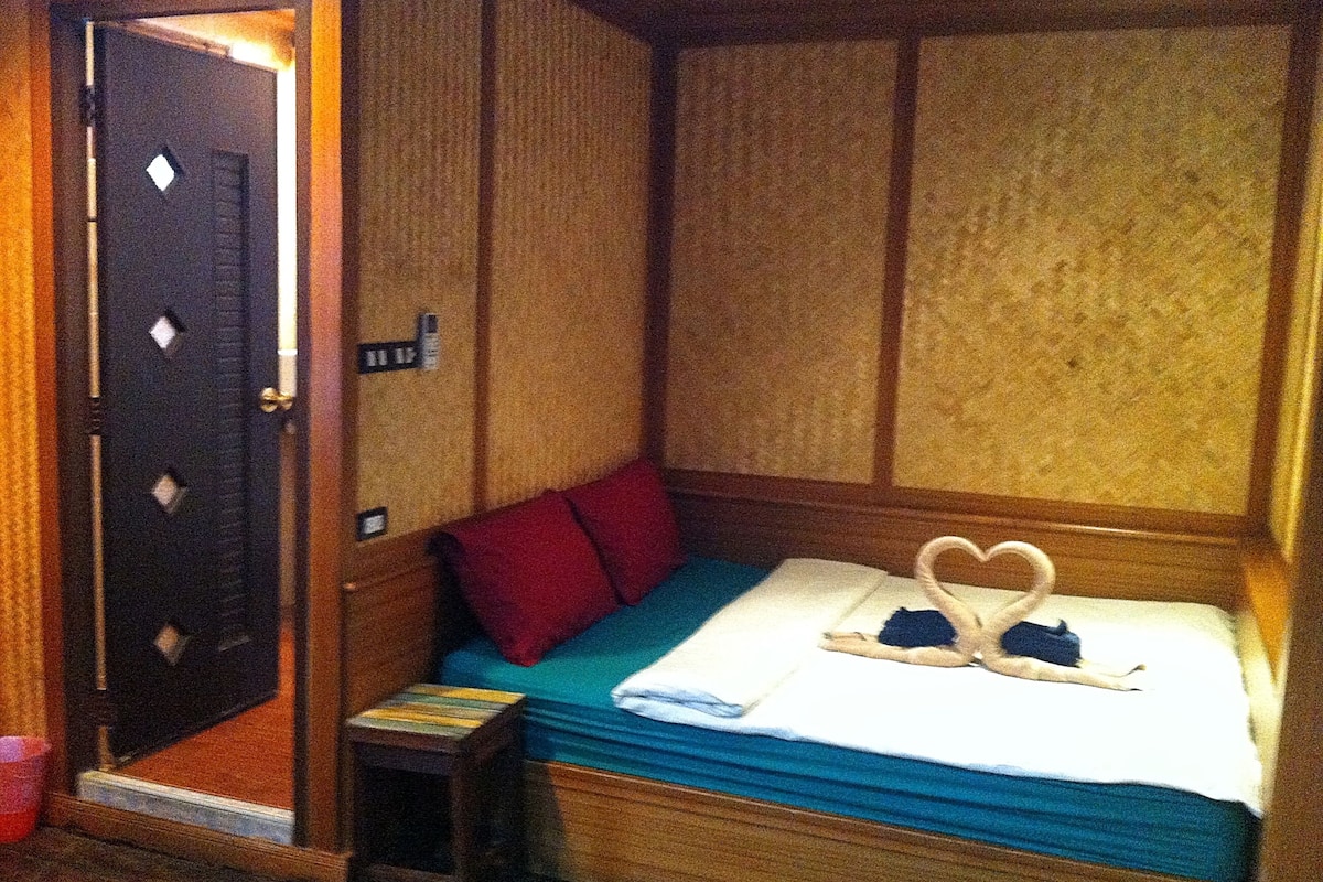 A small, cozy room with a bed, a small stool, and a door.