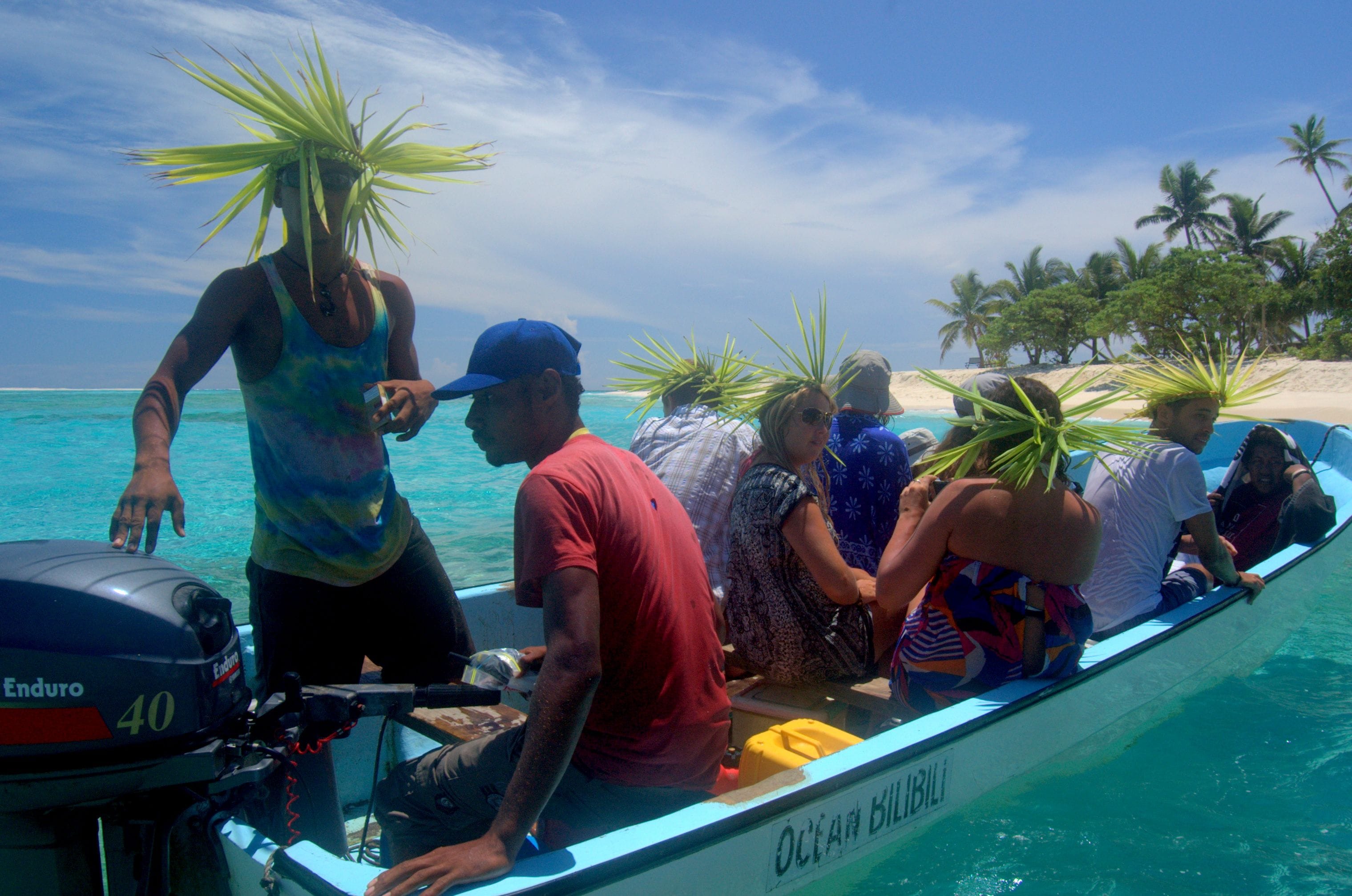 A boat with people wearing hats made of palm leaves, a motor labeled "Enduro 40", and a sign reading "OCEAN BILLABONG".