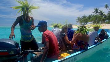 A boat with people wearing hats made of palm leaves, a motor labeled "Enduro 40", and a sign reading "OCEAN BILLABONG".