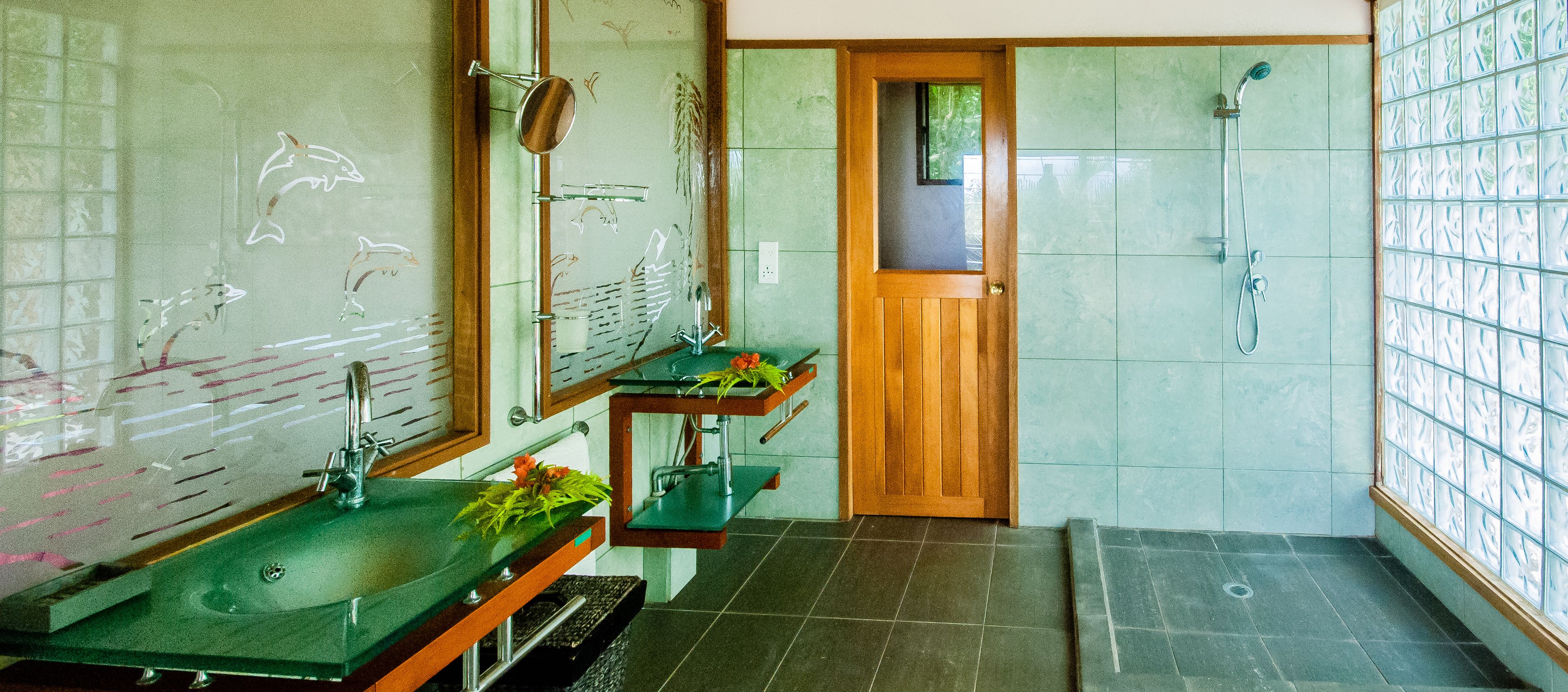 Een badkamer met een groene wastafel, een houten deur en een douchehoek.