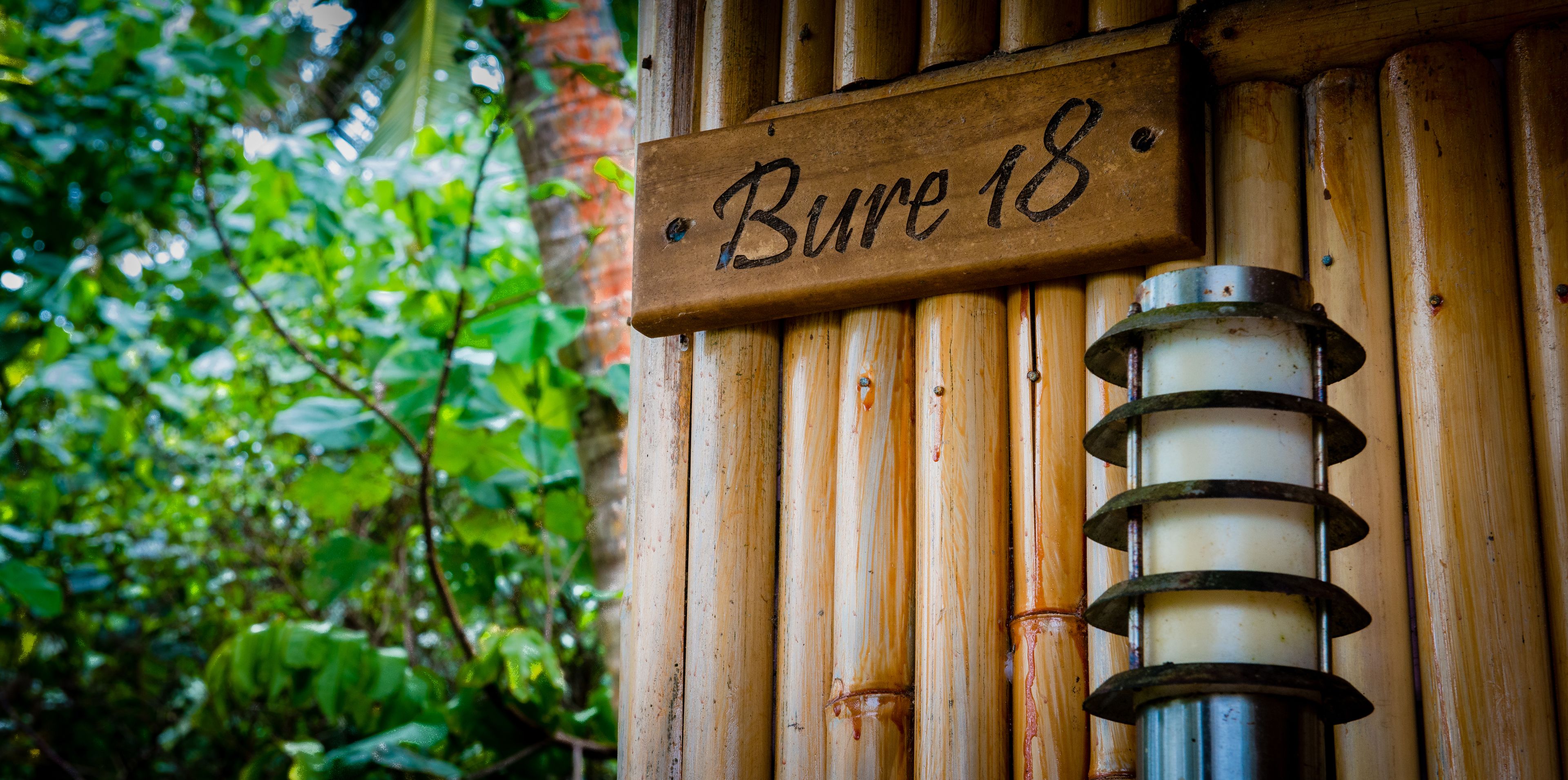 A wooden sign with the text "Bure 18" mounted on a wall with vertical wooden slats.