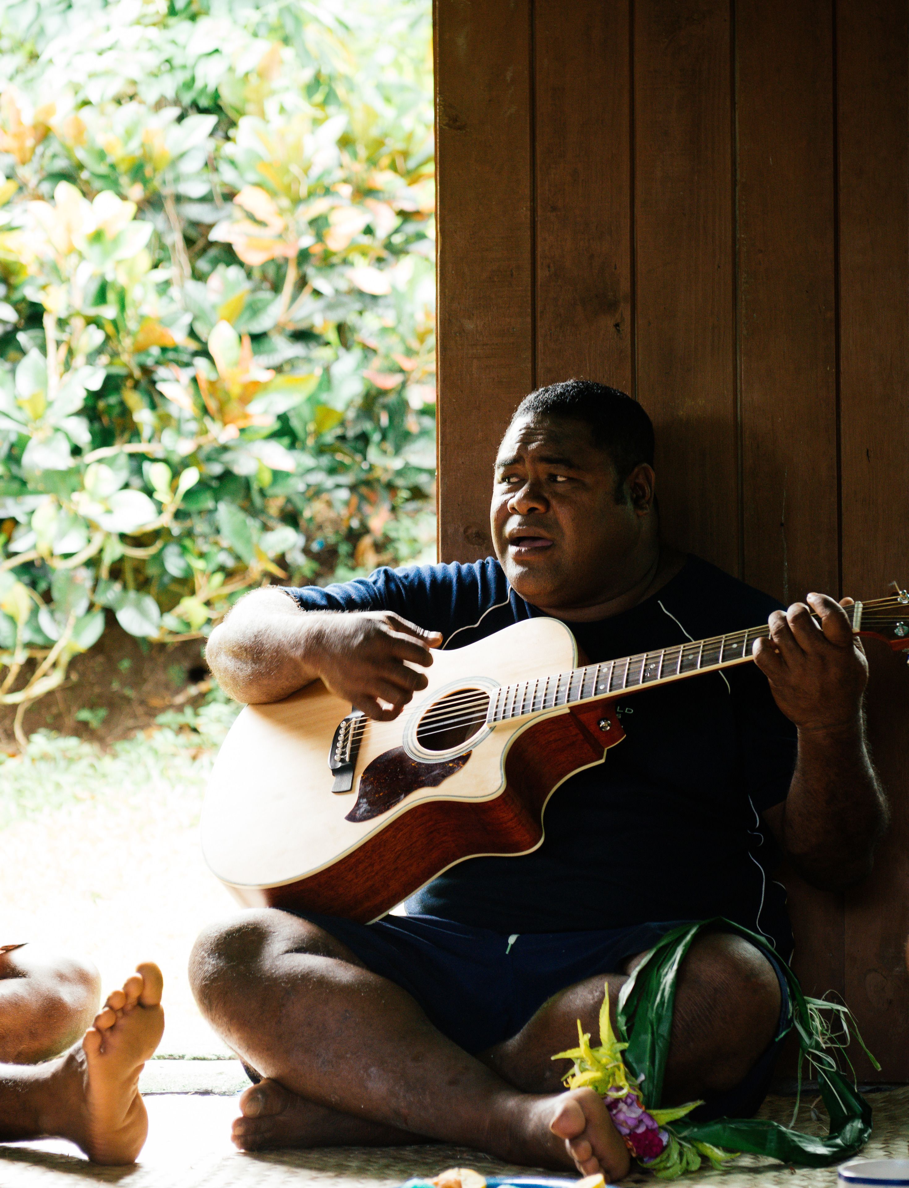 A person sitting on the floor playing an acoustic guitar.
