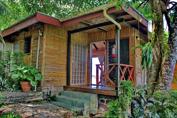 A wooden cabin with a porch, steps leading to the entrance, and a potted plant nearby.
