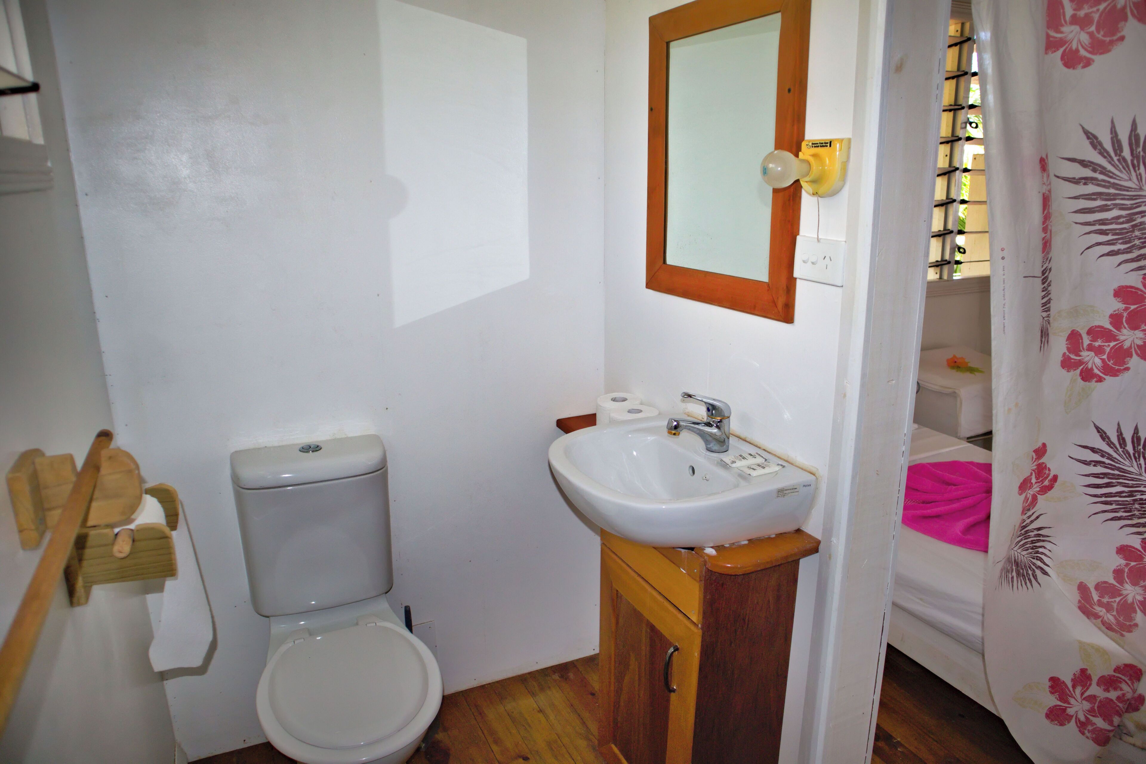 A small bathroom with a toilet, sink, and wooden cabinet.