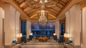 A spacious lobby with a high ceiling, large windows, and a central chandelier. - Hilton Bangkok Suvarnabhumi Golf Resort & Spa (Bang Phli)