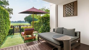 A modern outdoor seating area with a cushioned chair, a table, and a large umbrella. - Hilton Bangkok Suvarnabhumi Golf Resort & Spa (Bang Phli)