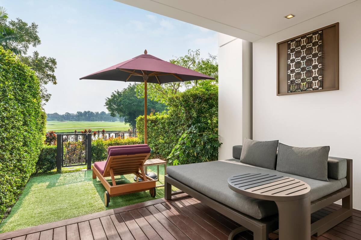 A modern outdoor seating area with a cushioned chair, a table, and a large umbrella.