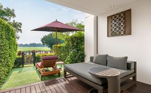 A modern outdoor seating area with a cushioned chair, a table, and a large umbrella.