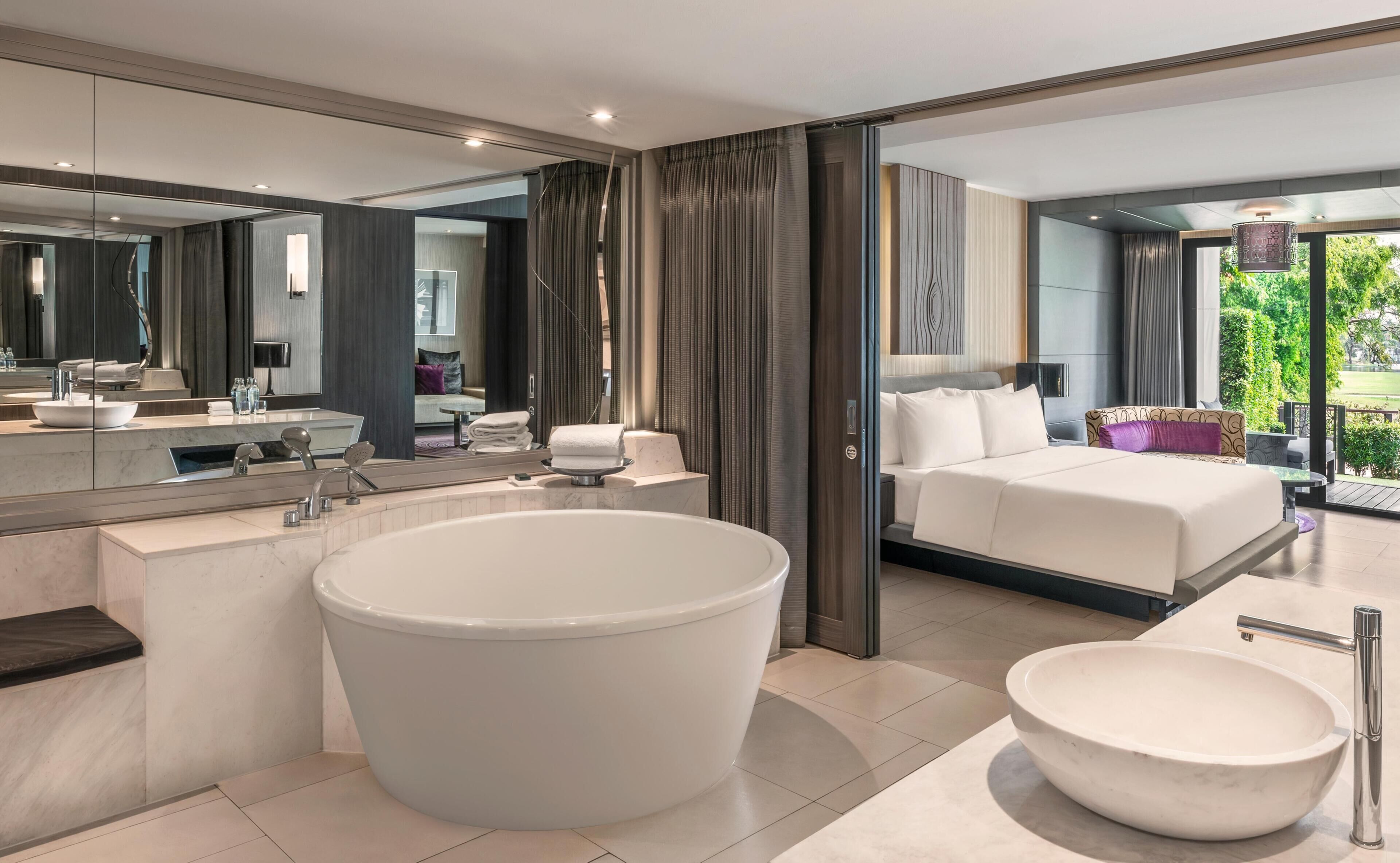 Un baño moderno con una bañera grande, un lavabo separado y un espejo.